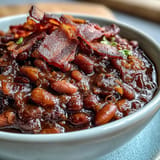Slow-cooked Juneteenth BBQ Baked Beans with bacon, a rich molasses aroma wafting.