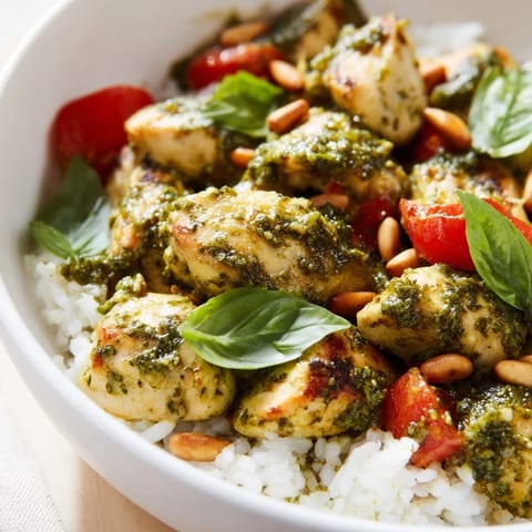 Warm Chicken Pesto Rice Bowl topped with toasted pine nuts and grated Parmesan, a vibrant gluten-free main dish.