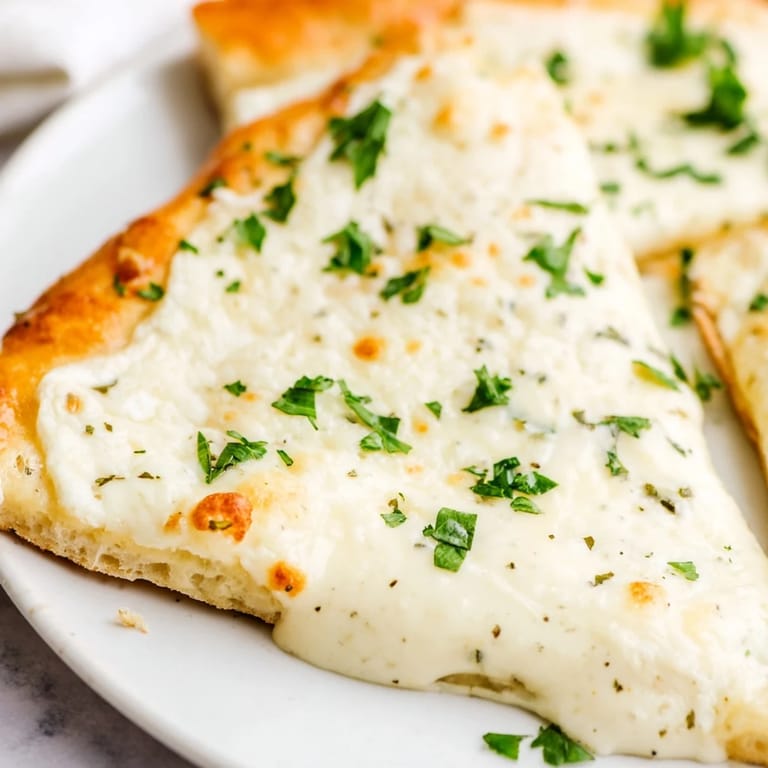 Thick, homemade garlic cream sauce spread over dough before baking creates a velvety, golden Creamy Garlic White Pizza.