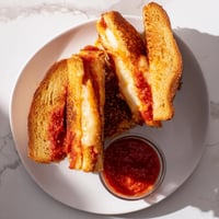 Golden-brown Mozzarella Stick Grilled Cheese with melted cheese and crispy sticks oozing out.  