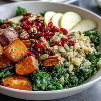 Massaged kale, roasted sweet potatoes, and quinoa in a vibrant Kale Harvest Grain Bowl with pomegranate seeds.
