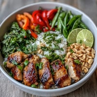 Thai Chicken Coconut Bowl with creamy rice, tender chicken, and crisp vegetables, garnished with peanuts and fresh herbs.